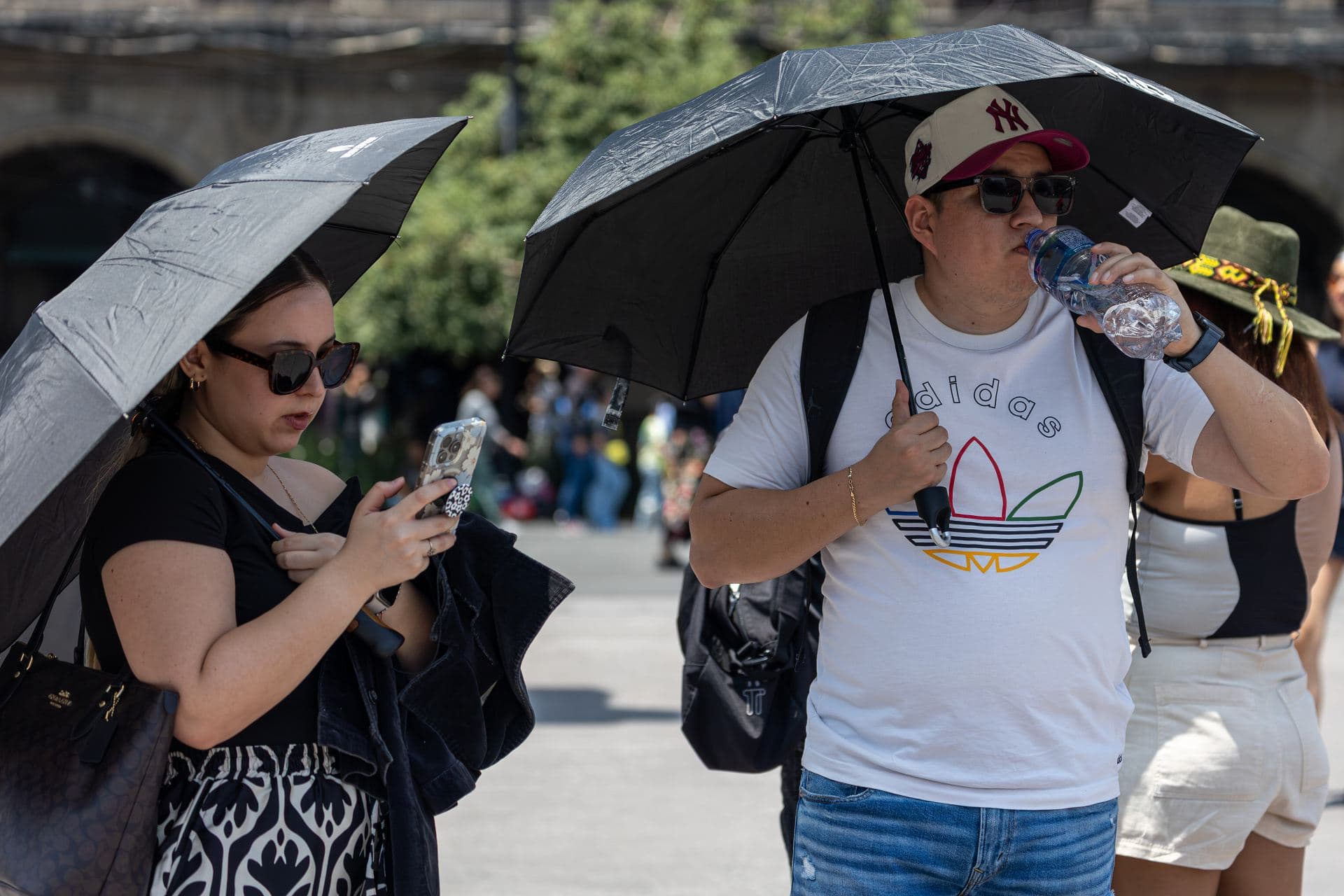 Personas con sombrilla por ola de calor en CDMX