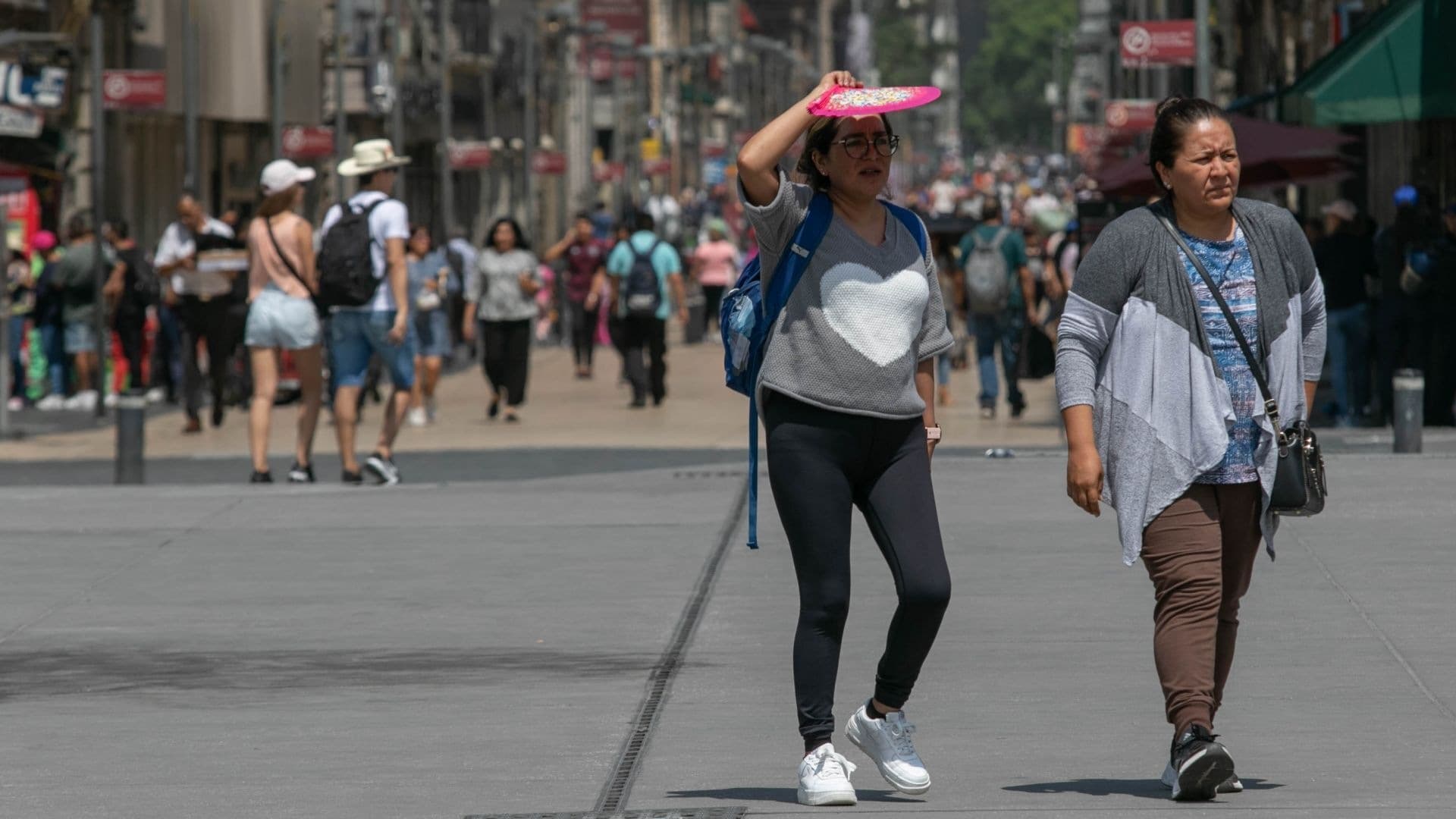 Dos personas caminan bajo el sol en medio de una ola de calor en la CDMX